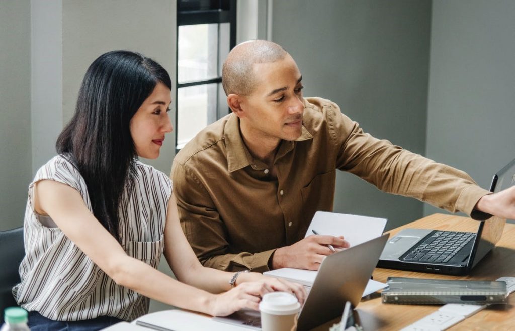 Two people working at a computer. 